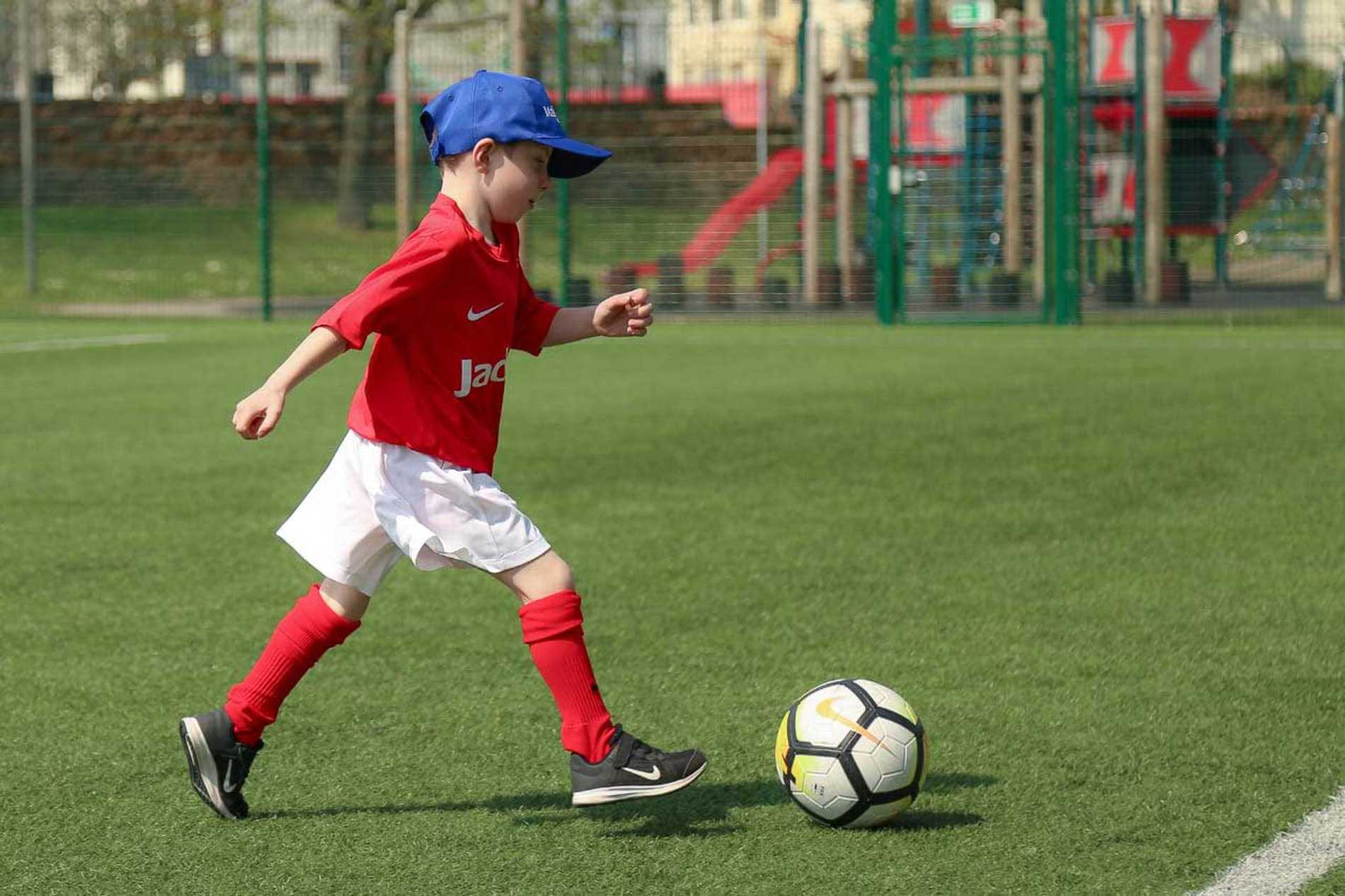 Wish child Jayden running with a ball on the football pitch