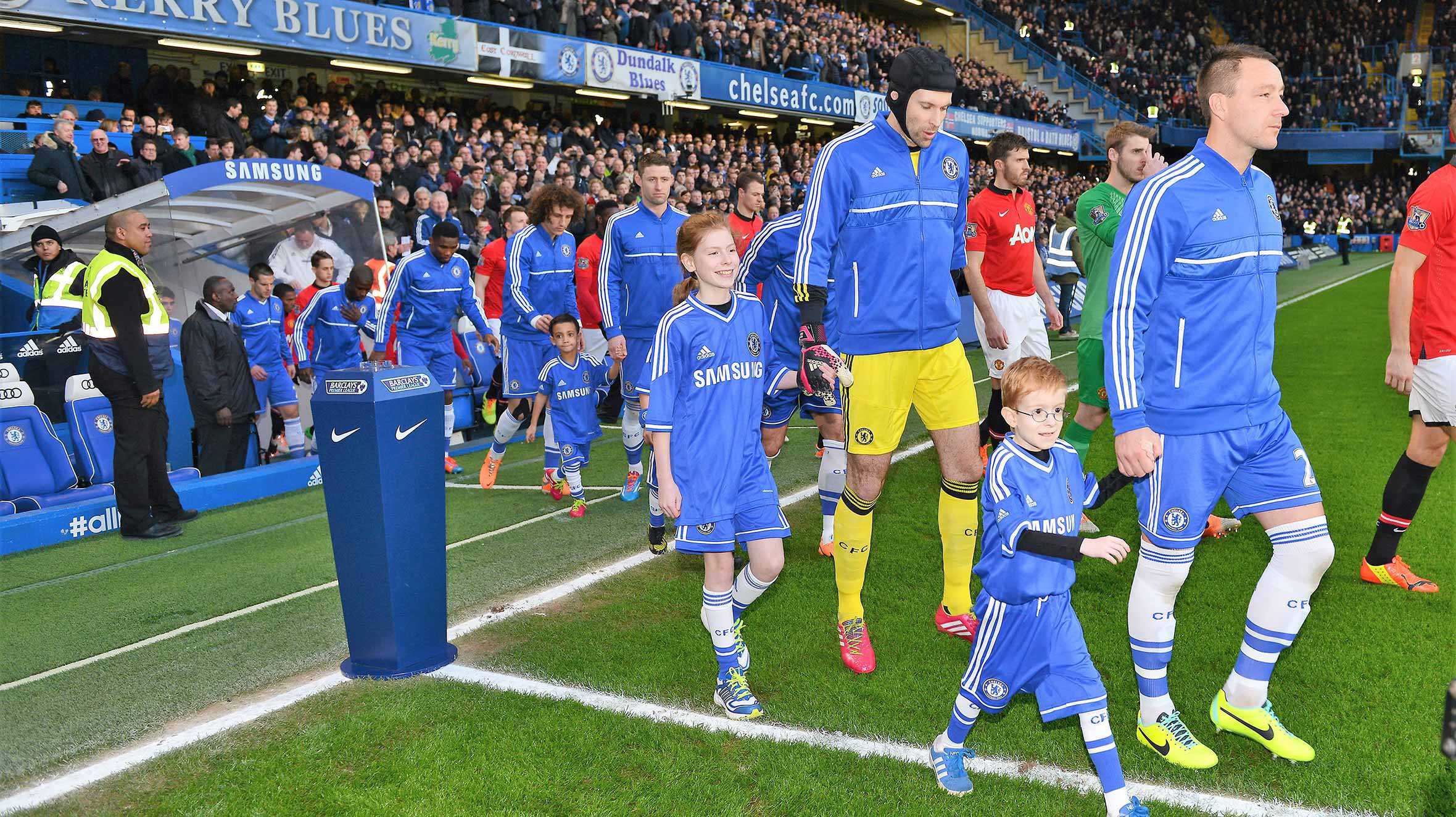 Oscar walking out with John Terry in front of the crowd at Stamford Bridge.