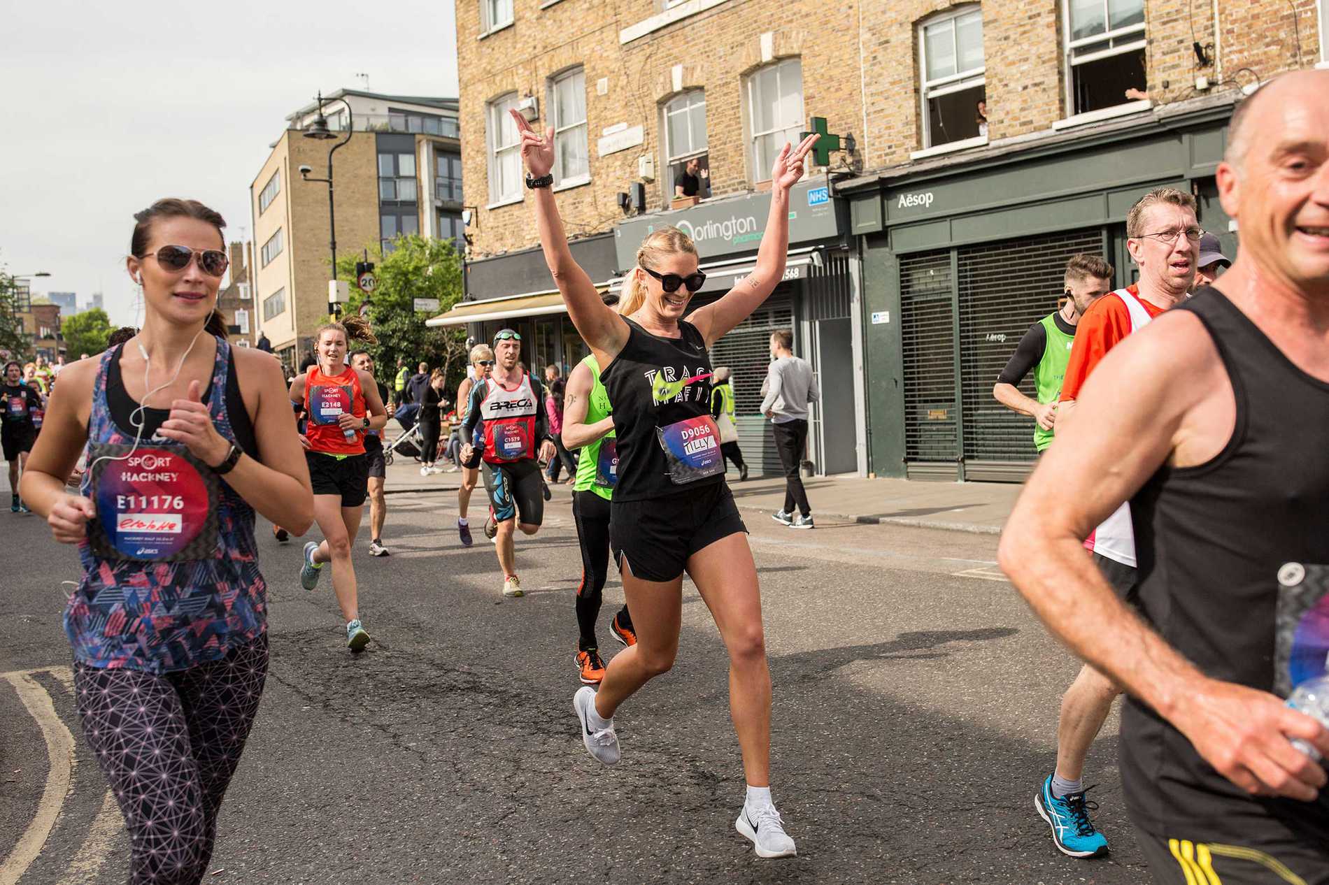 A runner with her hands in the air as she passes the camera during the Hackney Half Marathon.