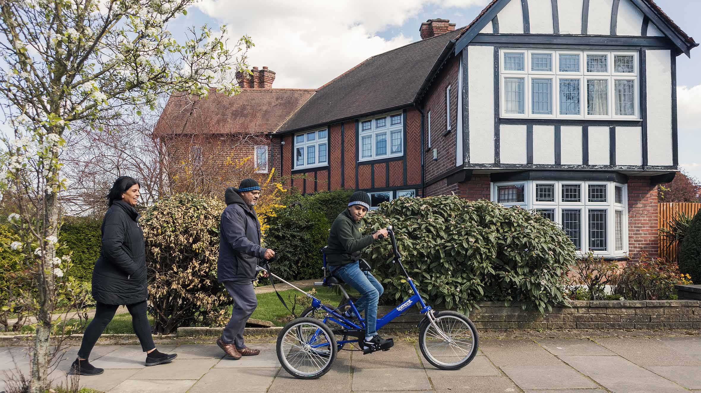 Aaryan cycling along the pavement as mum and dad follow behind on foot.