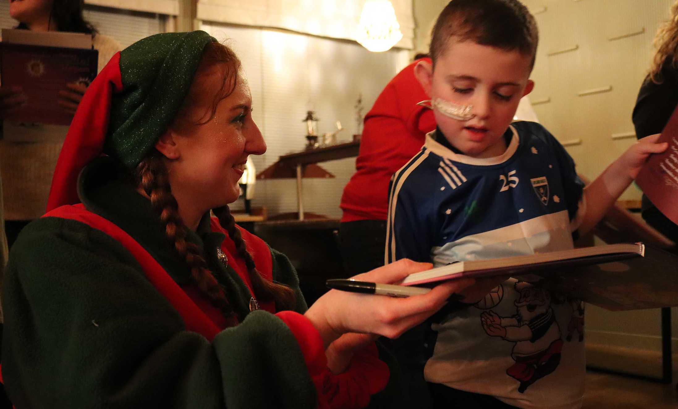 Tíernan being shown a book by one of Santa's helper's.