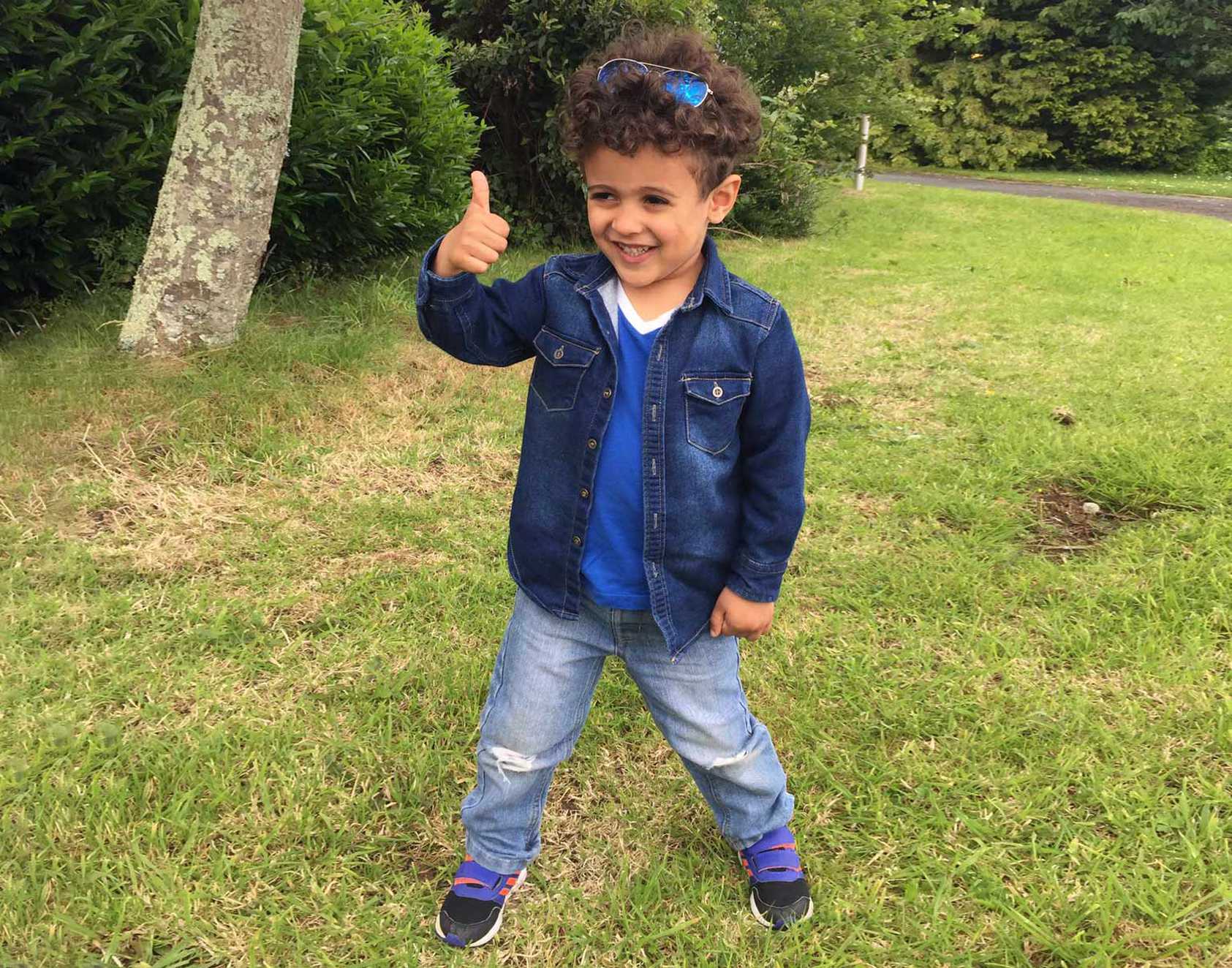 Wish Child Mohammad on the grass giving a thumbs up to the camera