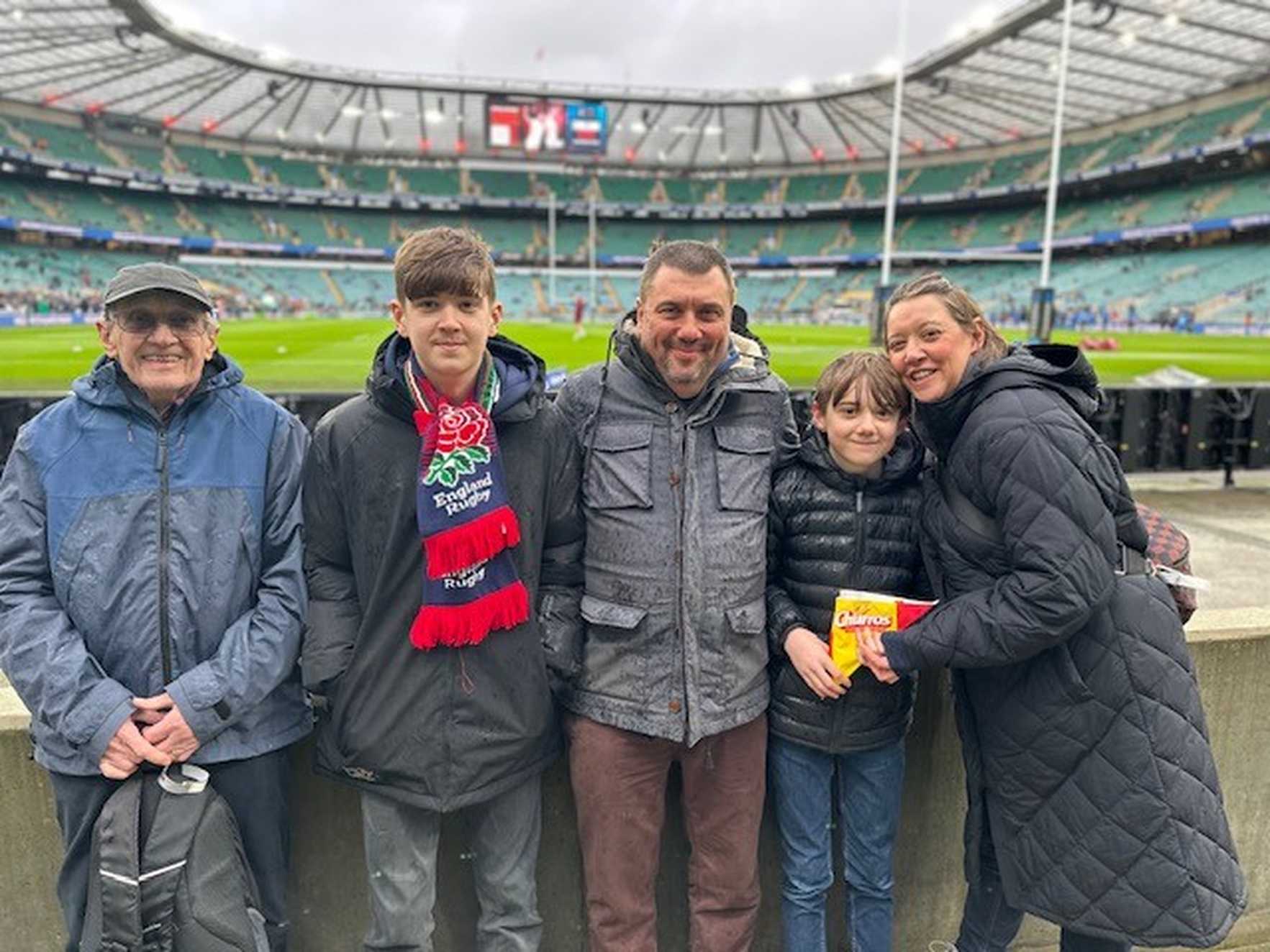 Seth, his mum, dad, brother and grandfather smile for a group photo behind the posts at Twickenham
