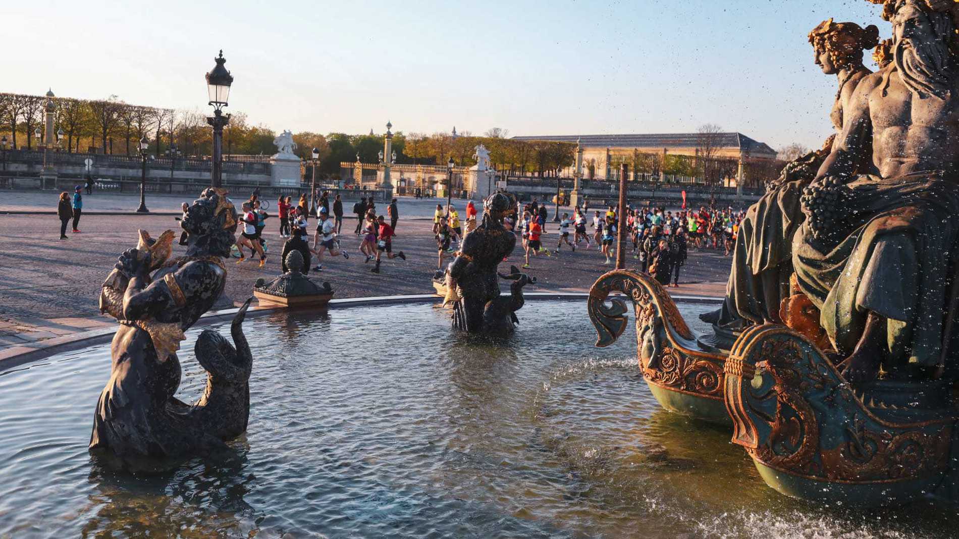 Runners passing an ornate fountain during the Paris Marathon.
