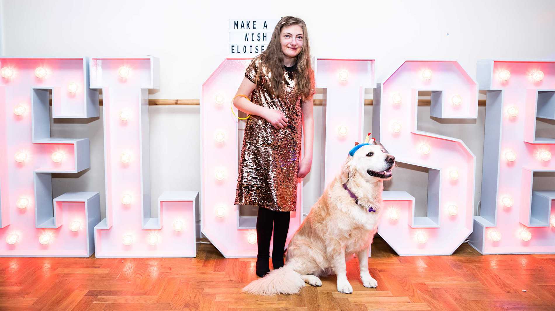Eloise and her Golden Retriever in front of her name, spelled out in large light up letters.