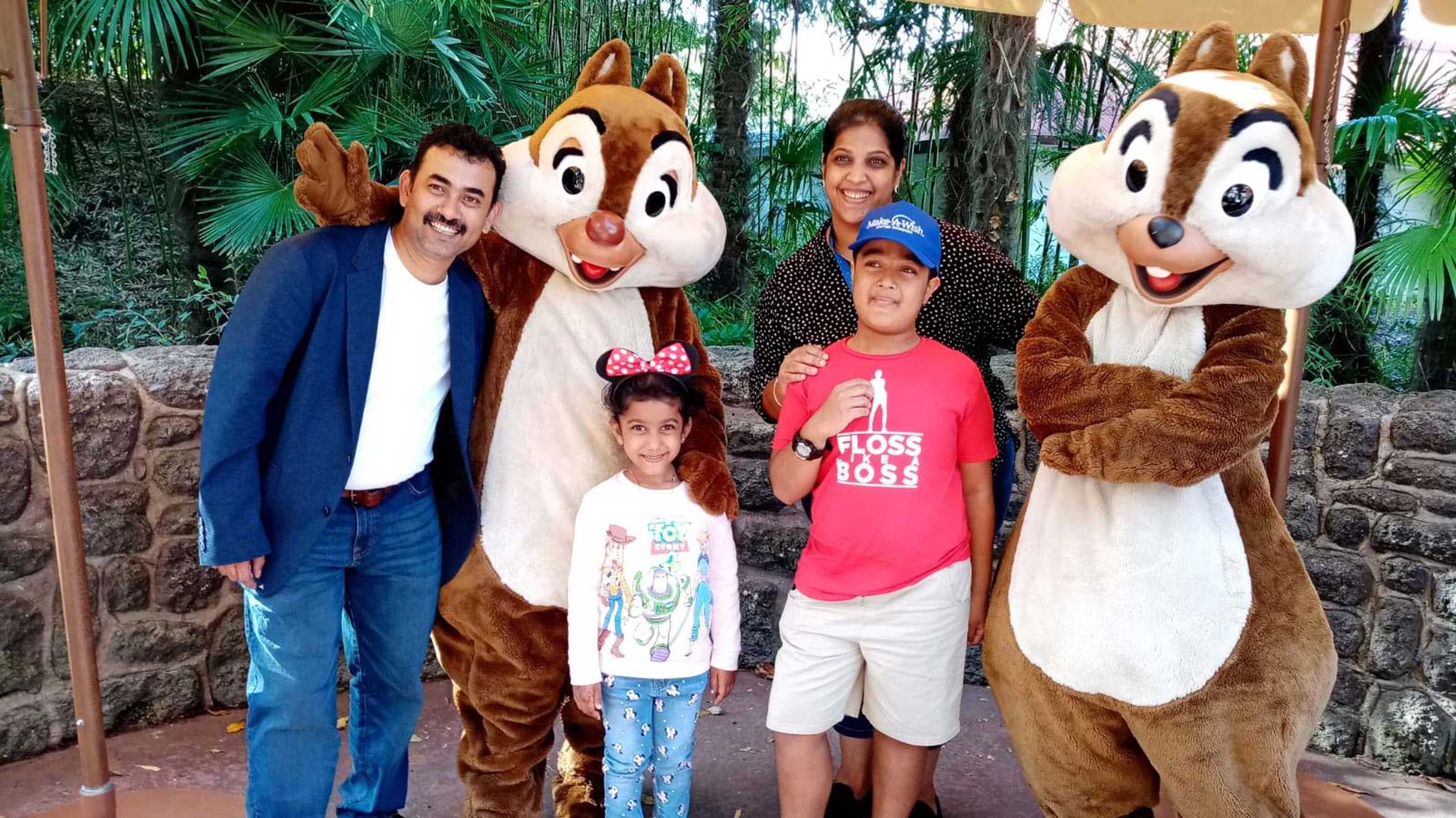 Abhi and his family posing with two chipmunk characters.